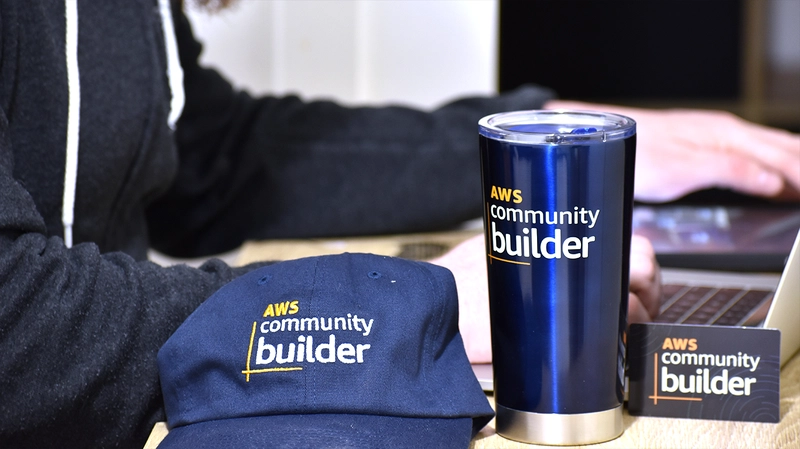 AWS Community Builder Swag 摆放在桌子上，包括一顶帽子、一个保温杯和一张卡片
