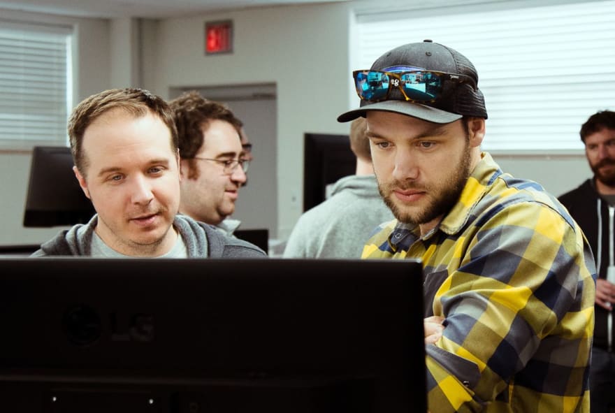 两个男人在电脑屏幕上讨论 React 项目