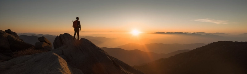 登山者登上山顶,眺望前方广袤无垠的山谷。
